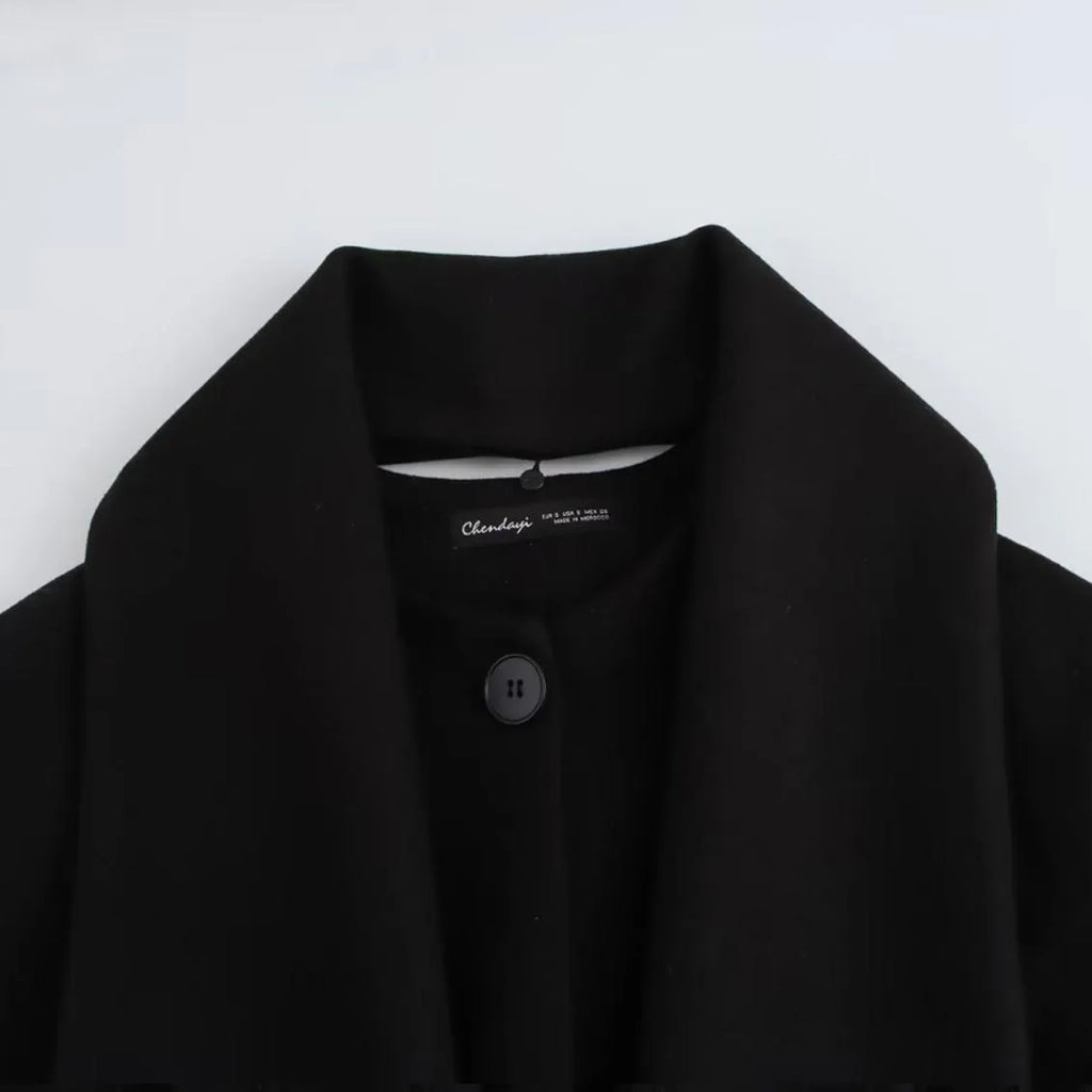 Women's long black polyester coat with a fluffy artificial fur collar, side pockets, and a street-fashion silhouette.