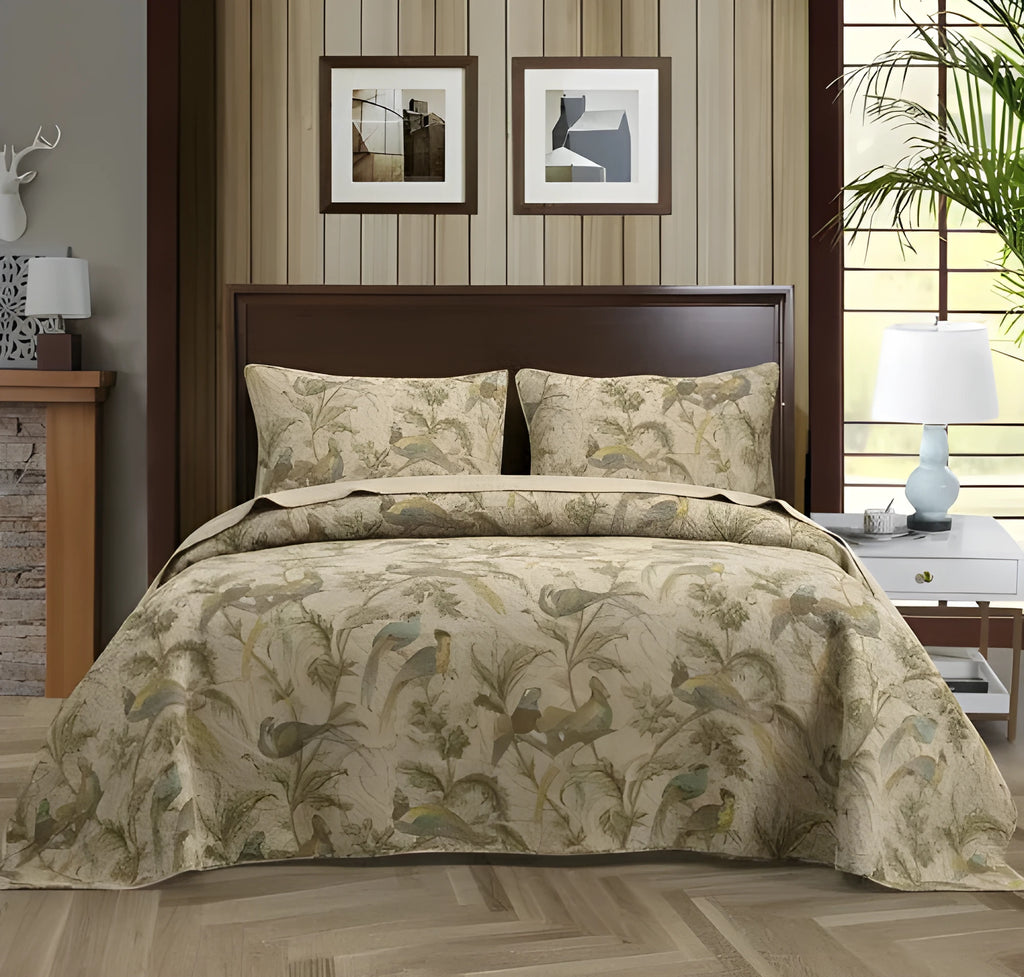 Blue cotton quilted bedspread with detailed floral and bird pattern, shown on a bed.