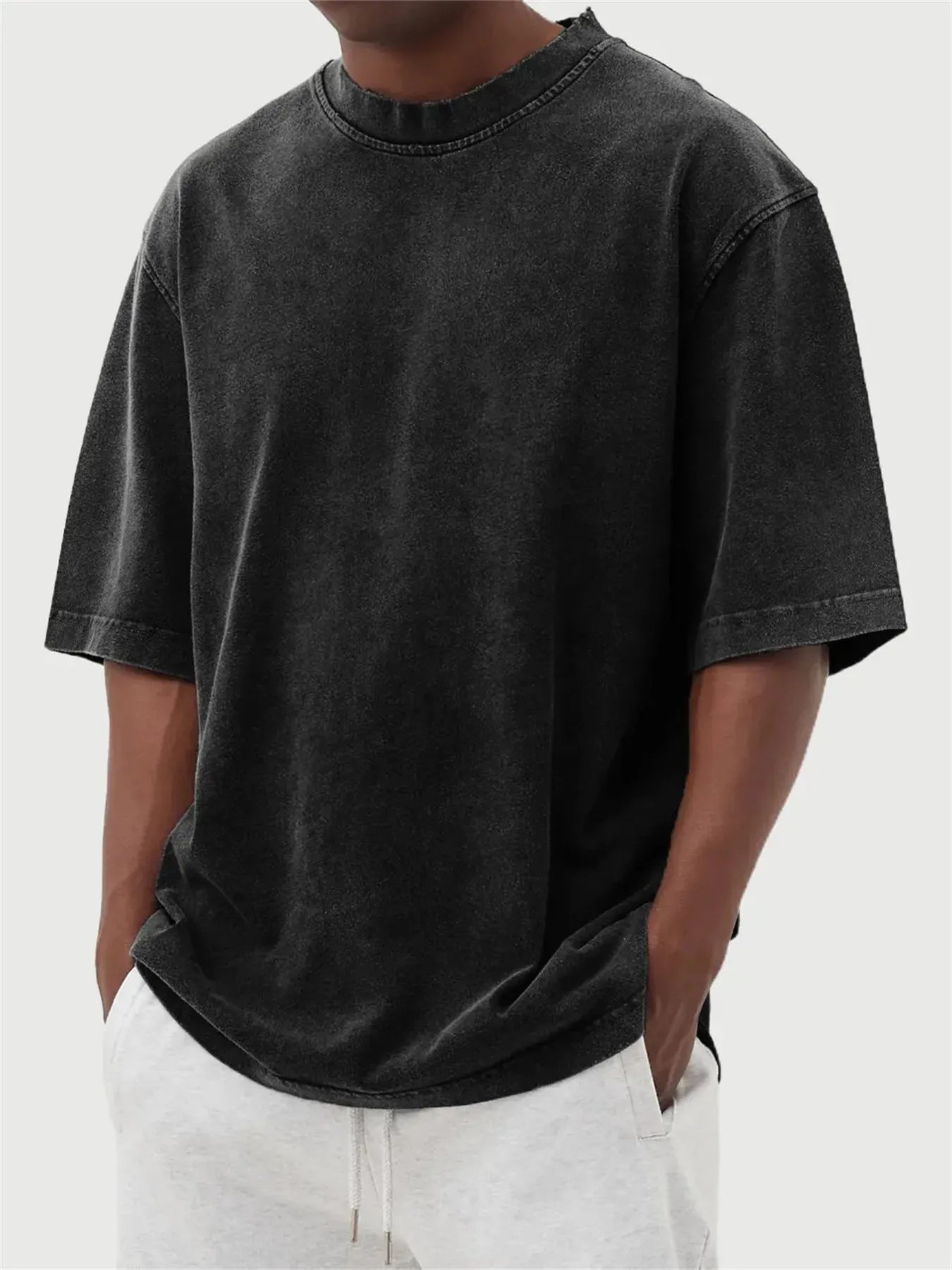 Man wearing a loose-fit, stone-washed grey t-shirt with a distressed solid colour finish and half sleeves.
