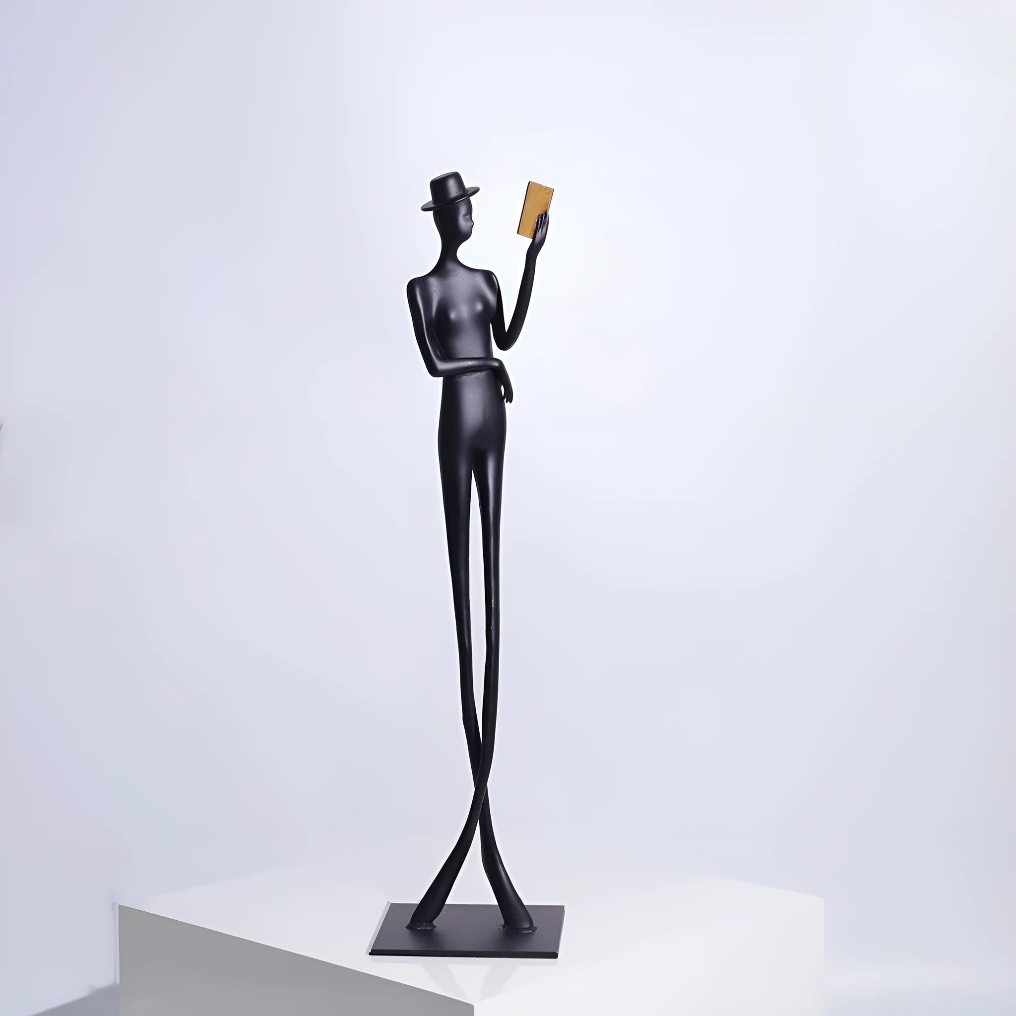 Black metal sculpture of a seated woman reading a book, modern minimalist desk decor.