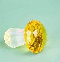 Set of four colourful crystal mushroom decorations in transparent, green, red, and yellow on a white background.