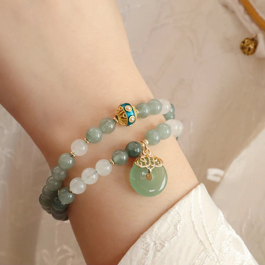 Close-up of a women's Myanmar jade bracelet with a geometric metal safety buckle pendant and lucky beads.