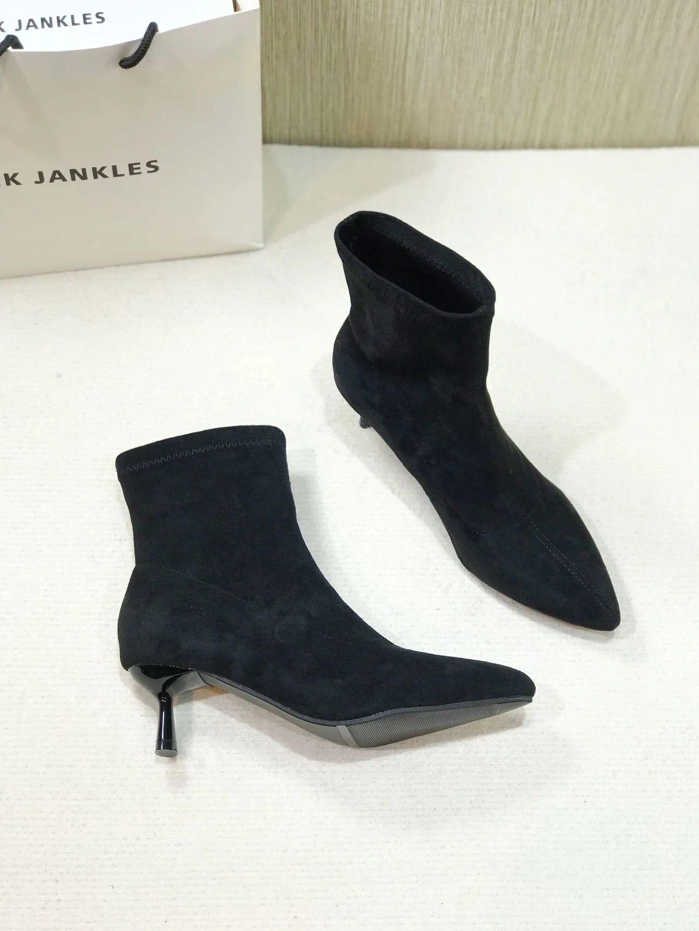 Black pointed toe women's ankle boots with a high stiletto heel on a rubber sole.