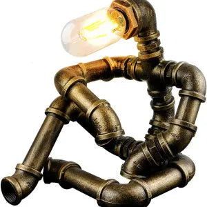 Green bronze vintage industrial iron pipe desk lamp on a wooden table.