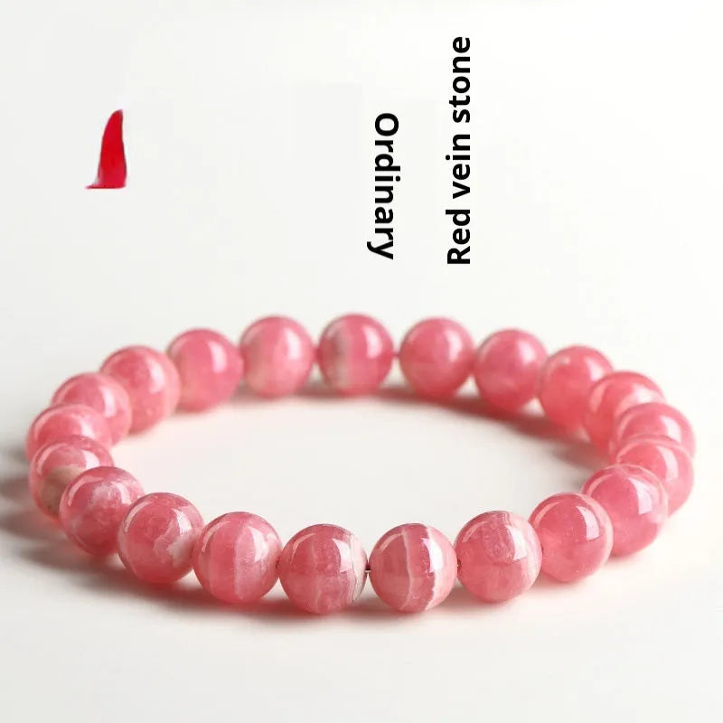 Women's geometric rhodochrosite crystal bracelet with a longevity lock charm on a wrist.