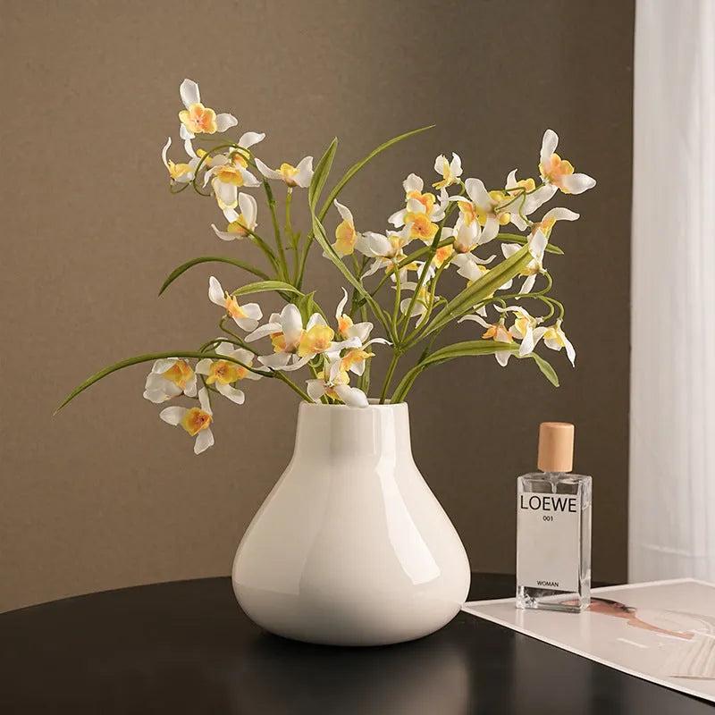 Ceramic decorative vase with coloured glaze surface and artificial orchid flowers in black or white colour