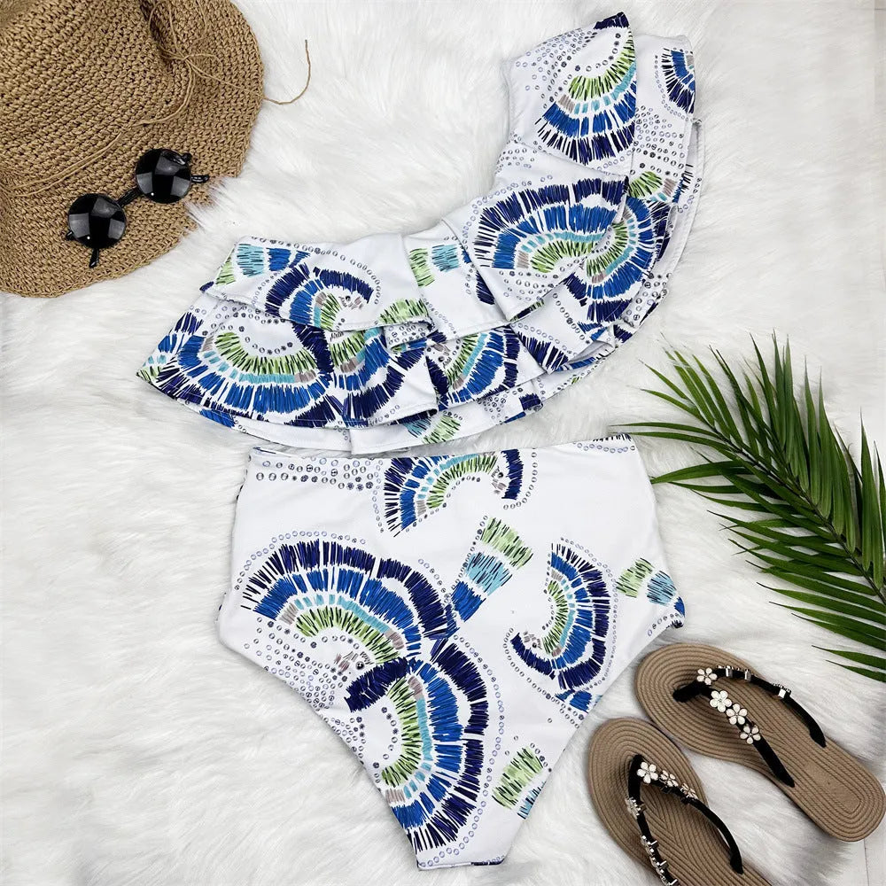 White women's one-shoulder bikini with a large lotus leaf ruffle and high-cut split leg briefs.