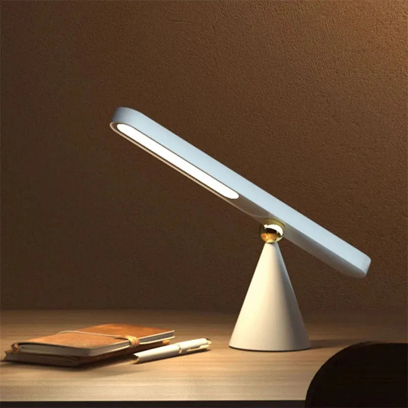 White geometric table lamp with touch switch and USB cable on a wooden desk.