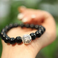 Close-up of a women's bracelet with spherical black agate beads and a shiny sterling silver clasp on a wrist.
