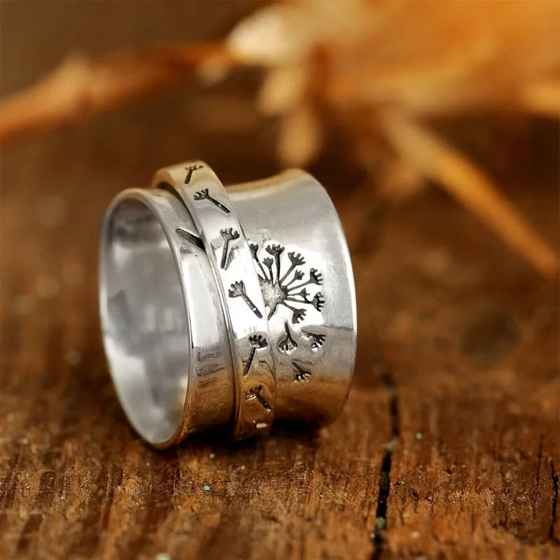 Silver coloured alloy flower ring with rotatable floral detail on a finger.