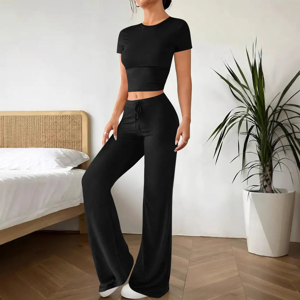 Black women's high waist trousers and short sleeve t-shirt co-ord set laid flat.