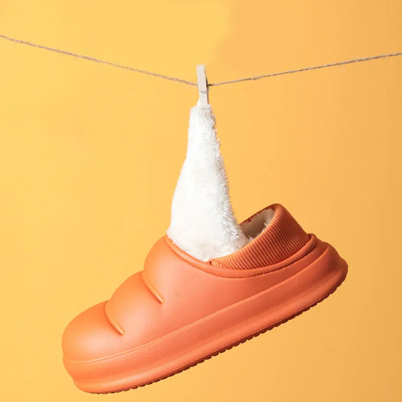 Green waterproof EVA garden slippers with plush lining and a non-slip sole, shown on a wooden deck.