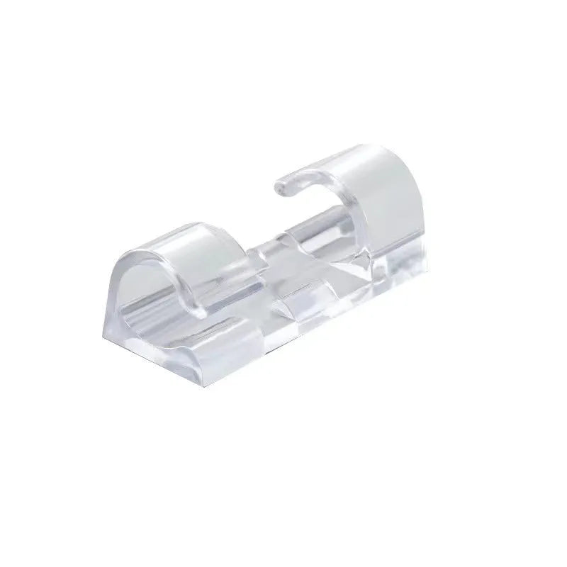 Transparent plastic self-adhesive cable clip holding a white wire against a wall.
