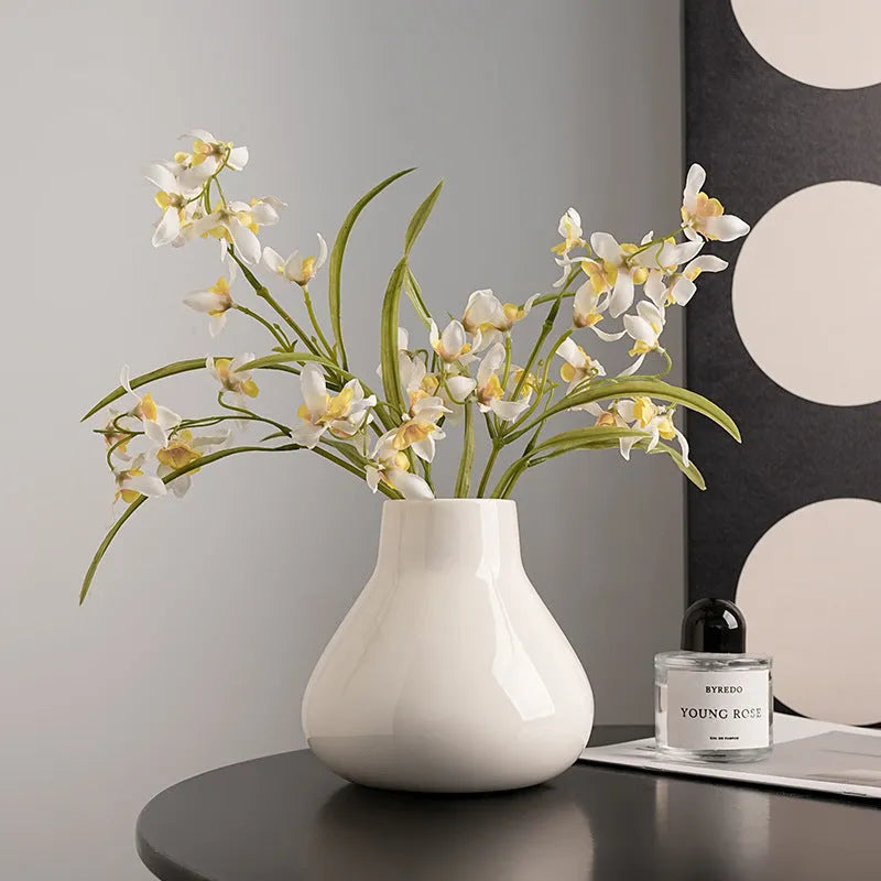 Ceramic decorative vase with coloured glaze surface and artificial orchid flowers in black or white colour