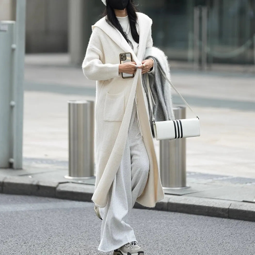 Long grey knitted hooded cardigan trench coat on a hanger, showing loose fit and long sleeves.