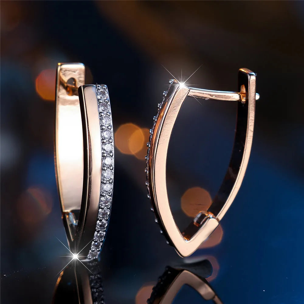 Close-up of women's geometric V-shaped clip-on earrings in champagne gold with white diamond details on a copper base.