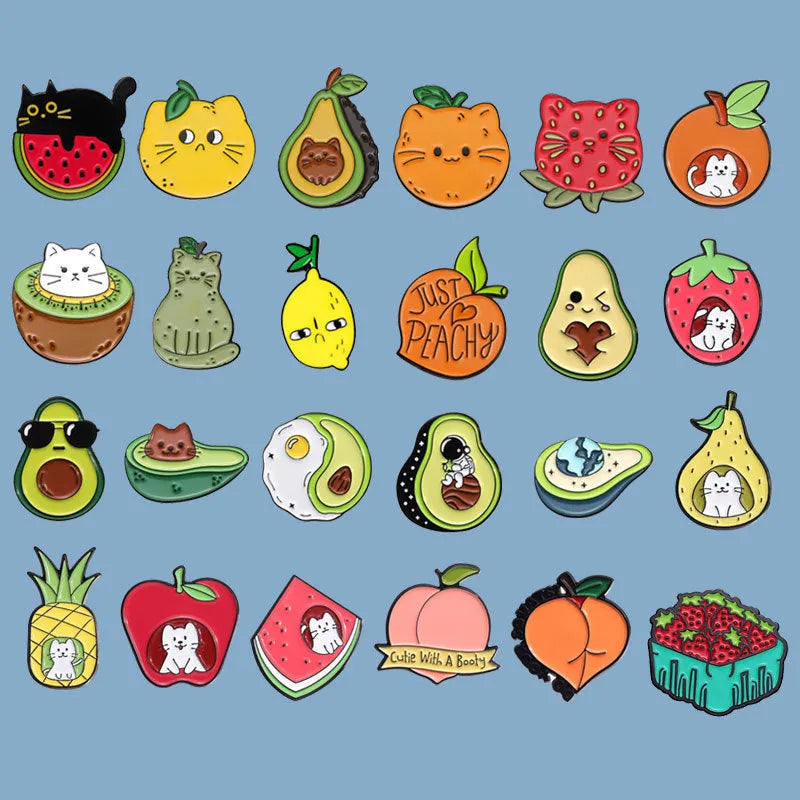 Colourful metal brooch with cartoon fruit and letter design on a blue background.