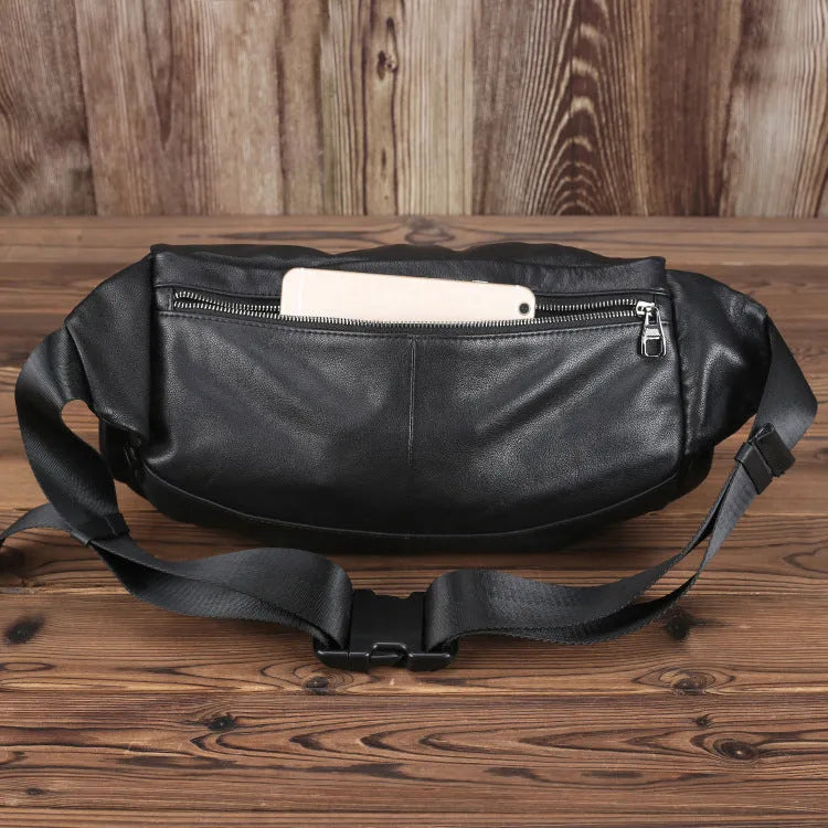 Black cowhide leather messenger bag with large capacity, oval shape, and zipper closure – worn over the shoulder as a crossbody bag