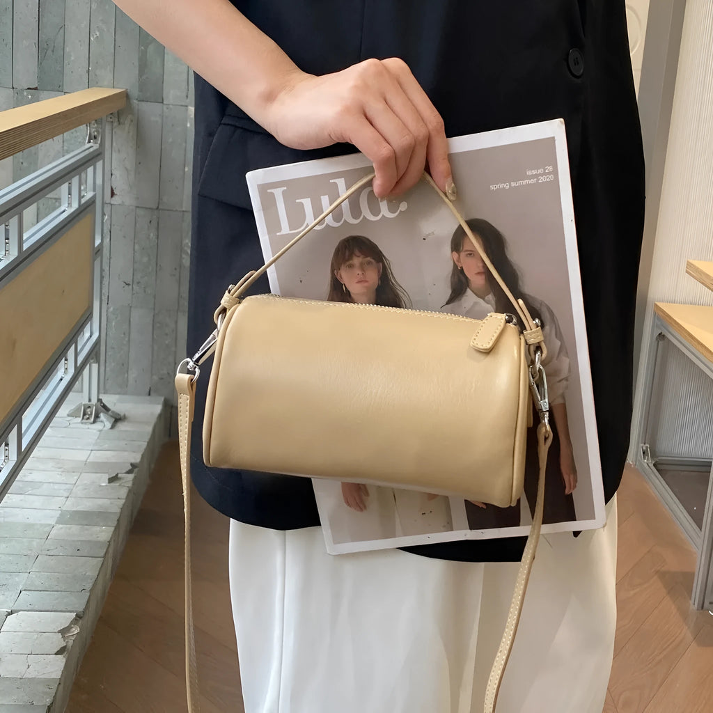 Soft genuine leather cylindrical crossbody phone bag in brown with a single shoulder strap.