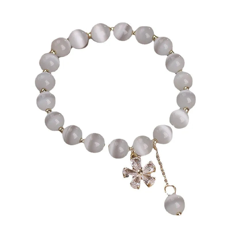 White cat's eye crystal bracelet for women with a small flower tassel and a morganite-coloured safety buckle.