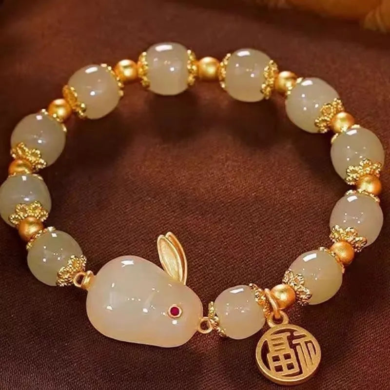 Green jade lucky bracelet with black hare charm, fu character, and lily flower on black adjustable cord.