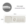 Silicone faucet splash guard pad in sloped design with drain channels on kitchen sink