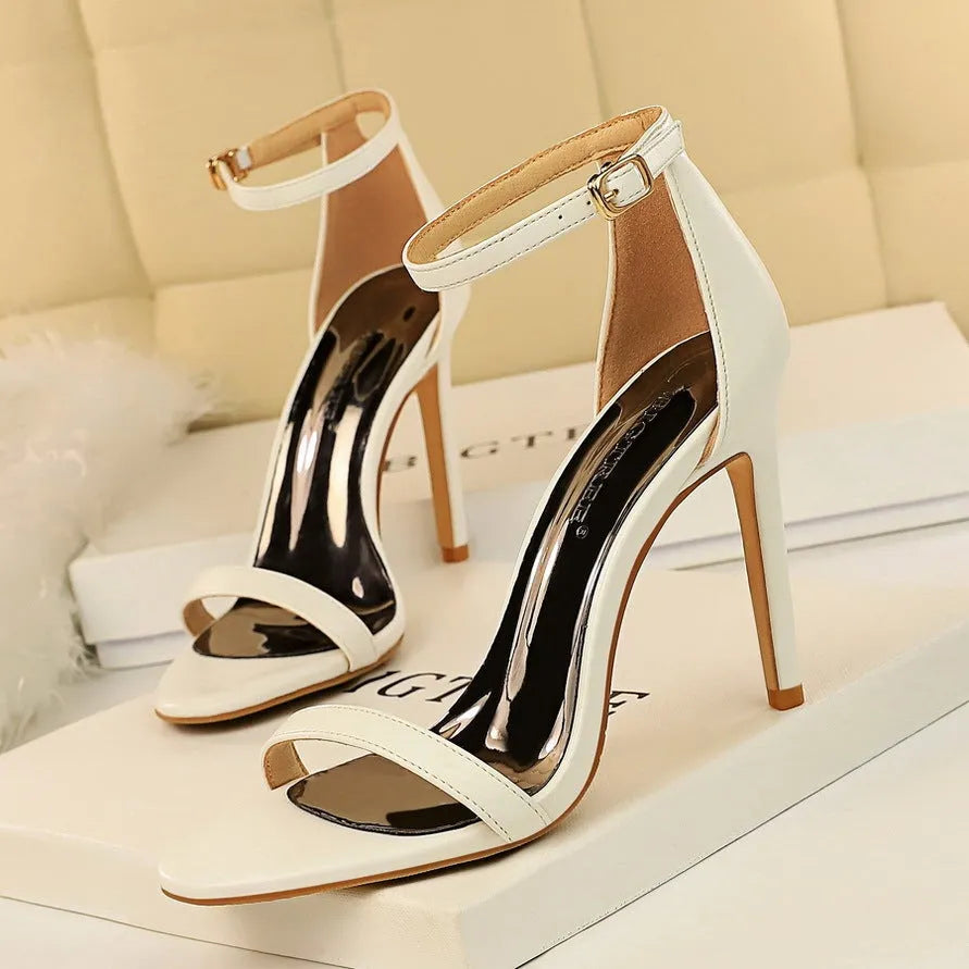 Women's ankle-strap high heel sandals in an open-toe design, showing buckle detail and available in multiple colours.