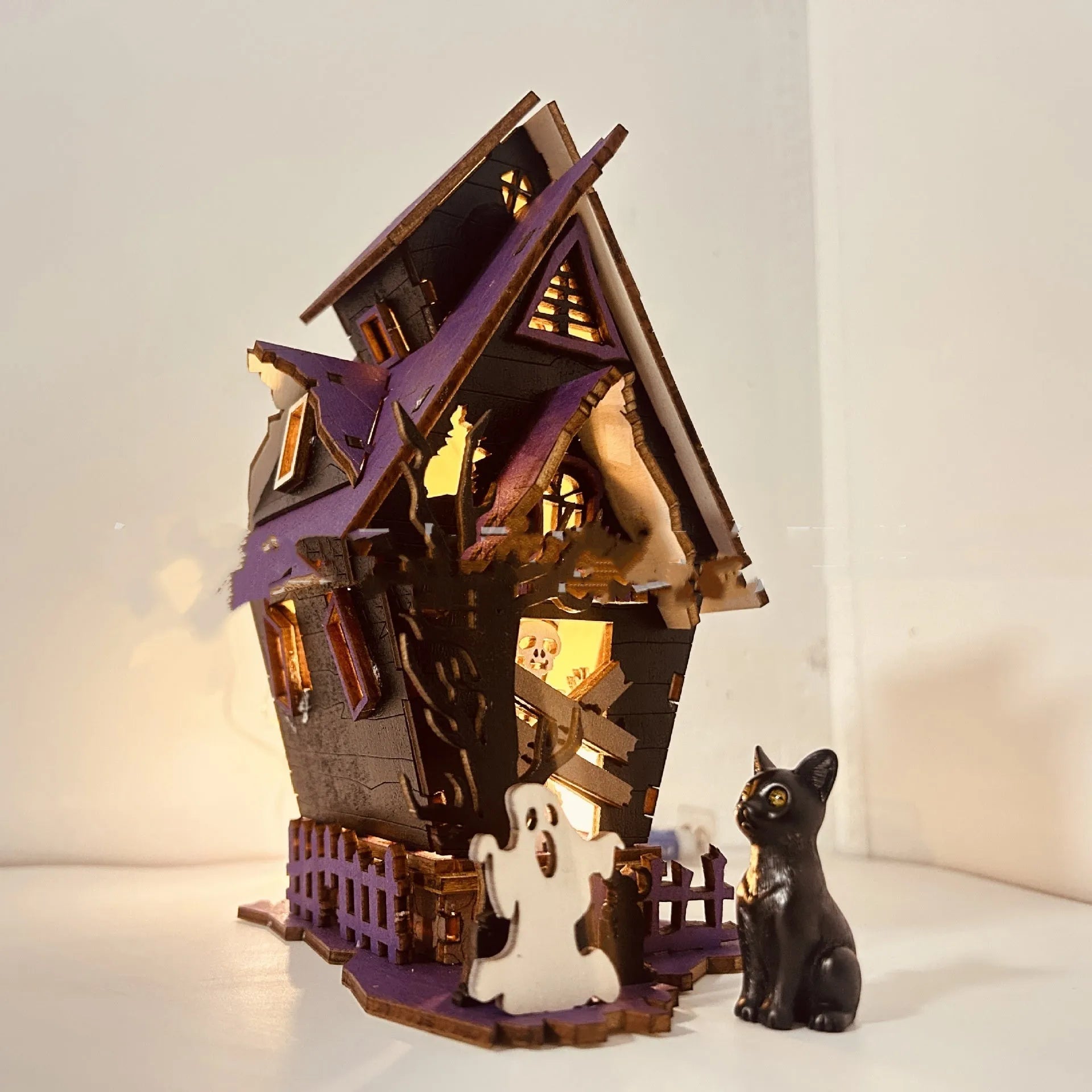 Wooden glowing haunted house Halloween table decoration on a dark surface