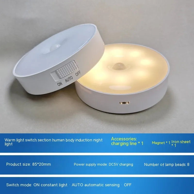 Small white circular motion sensing LED night light with adhesive backing next to a USB charging cable.