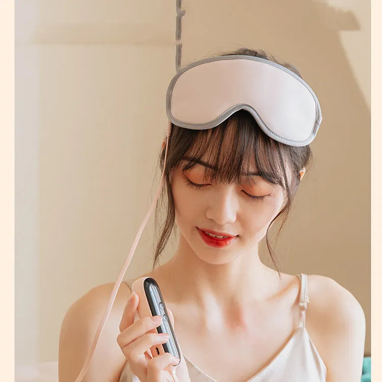 Green portable eye steam massage goggles with USB cable on a table.
