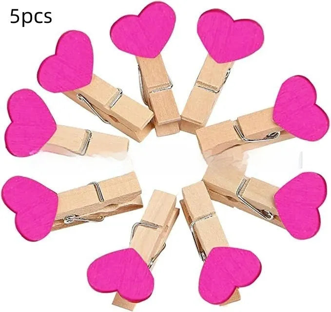 Five handmade solid wood heart-shaped clips in red, white, and pink on a wooden surface.