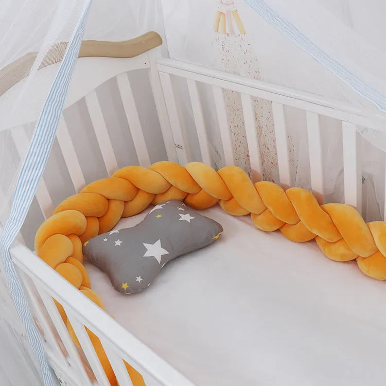 Braided knot baby crib bumper in spandex velvet wrapped around white cot rails.