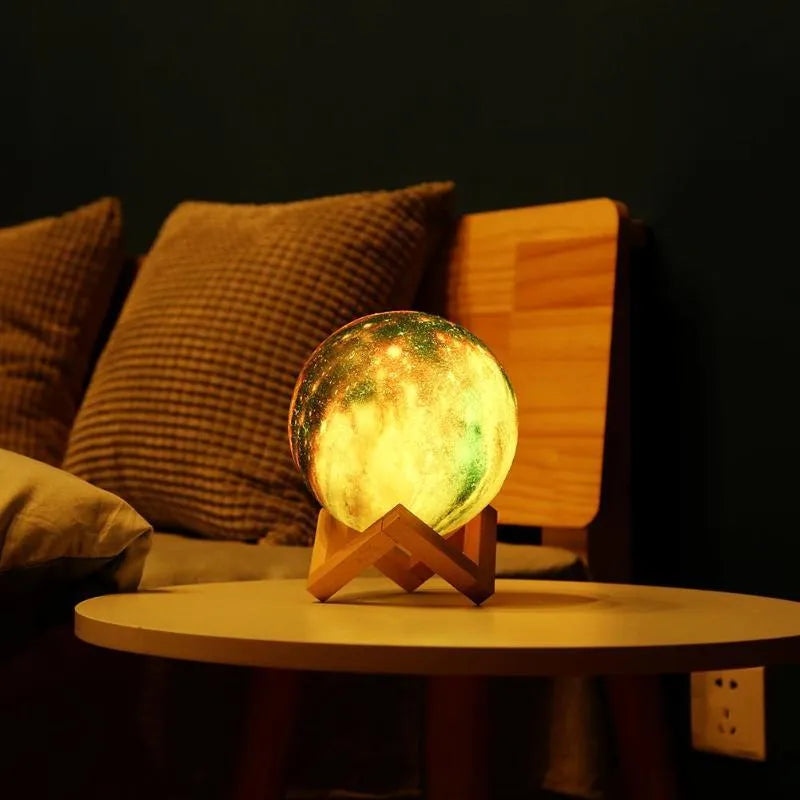 3D printed white lunar lamp sphere glowing on a surface, showing crater texture with a remote control nearby.