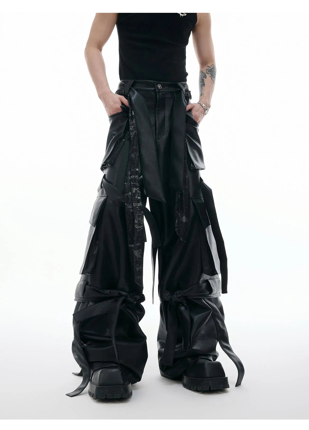 Black loose-fit men's trousers with multiple pockets, quilted panels, and decorative leather ribbon trim.
