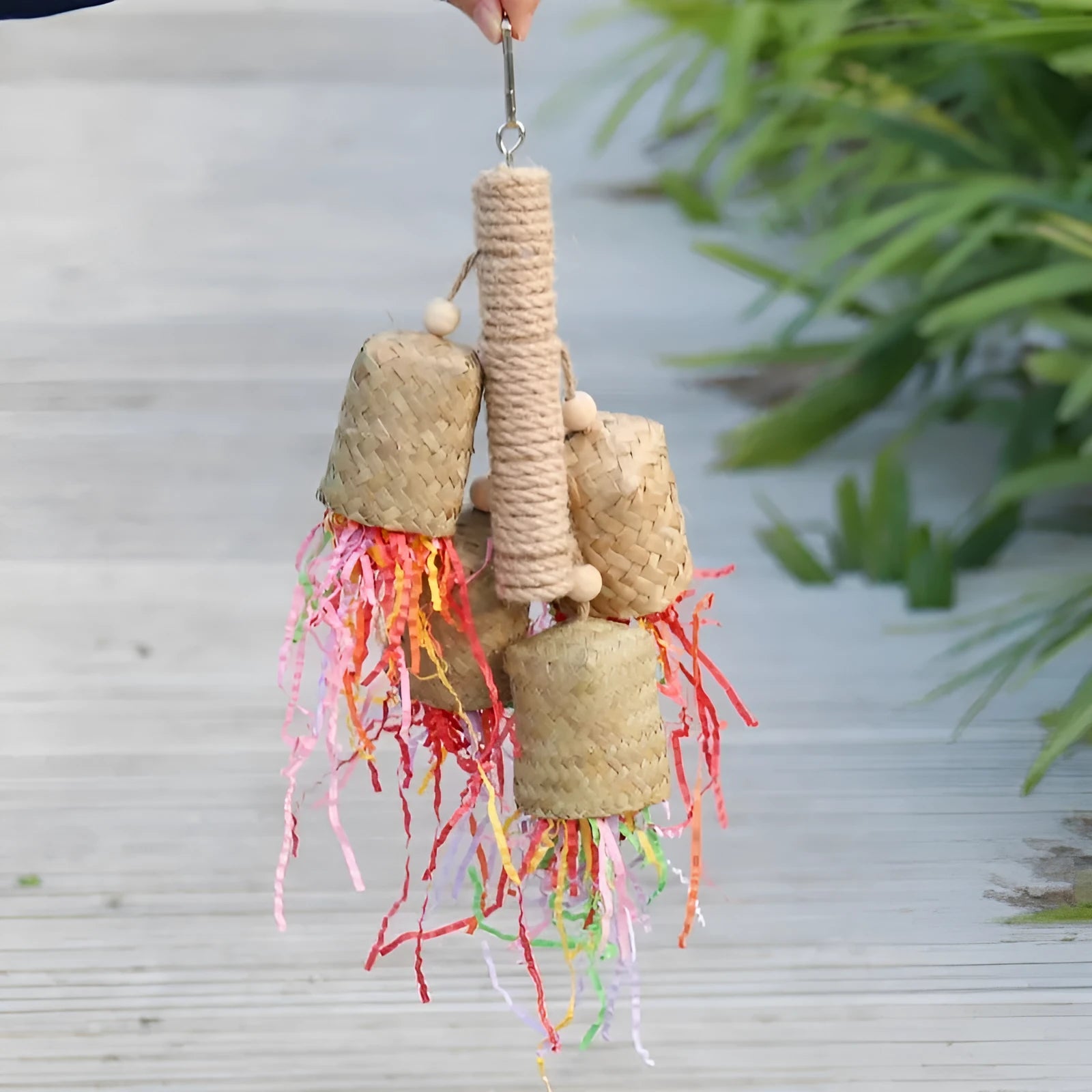 Wooden parrot toy with colourful shredded paper hanging by sisal rope