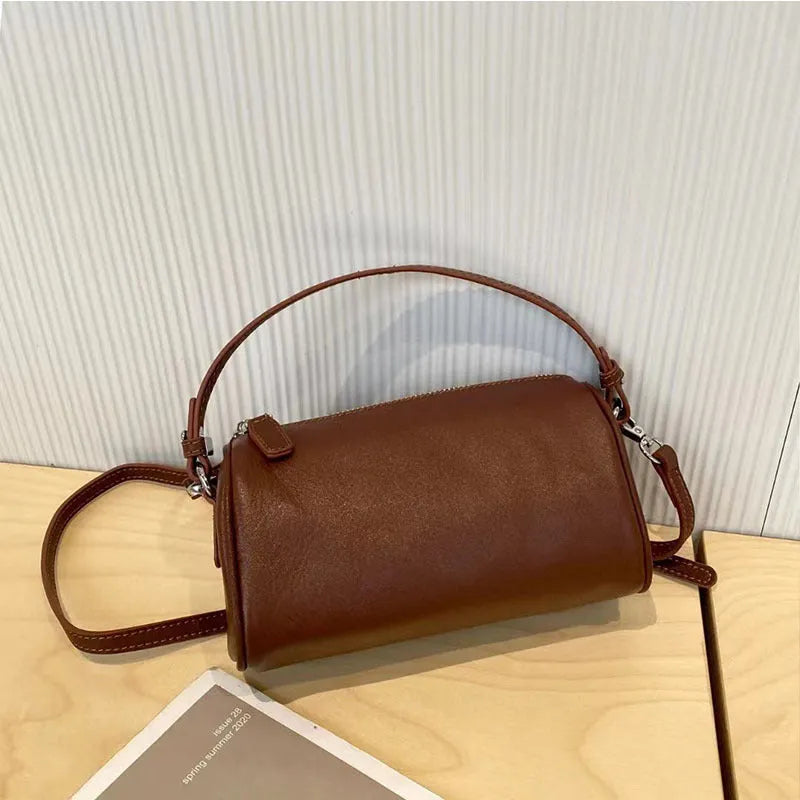 Soft genuine leather cylindrical crossbody phone bag in brown with a single shoulder strap.