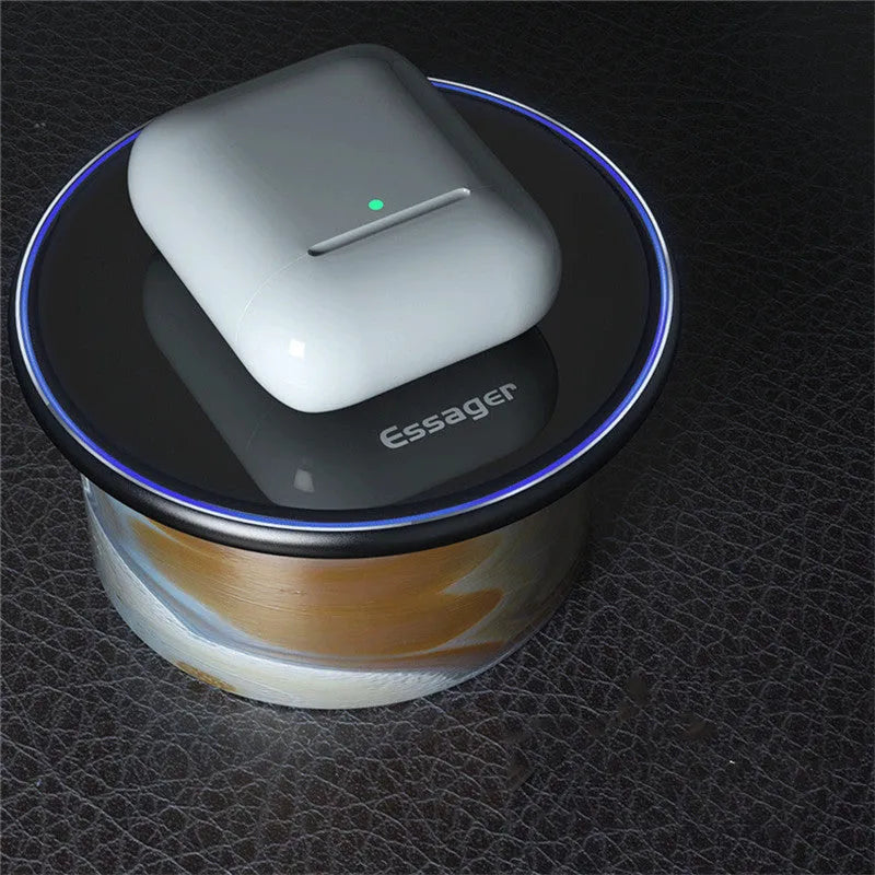 Black 15W fast wireless charging pad on a wooden desk next to a smartphone.