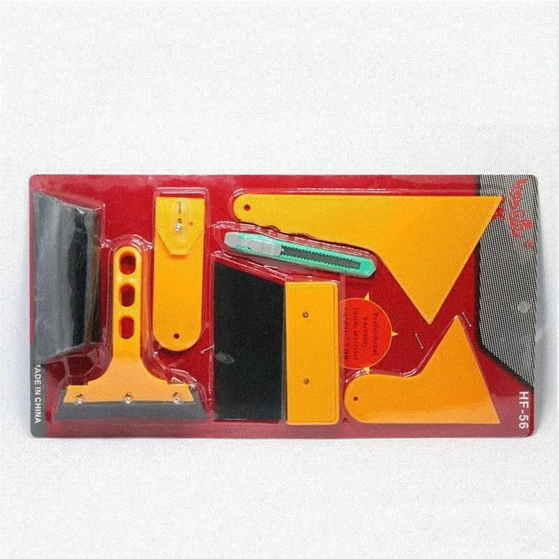 Seven-piece automotive film tool set with scrapers, knives, and a pressing block on a work surface.