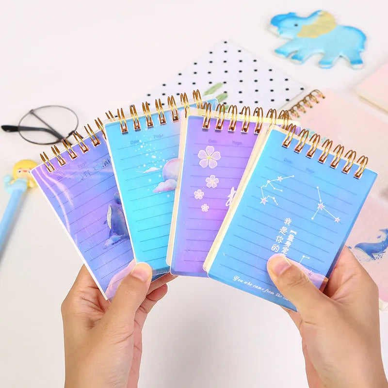 Set of four A7 spiral-bound pocket notebooks with different coloured PP covers showing Constellation, Sakura, Ocean, and Universe designs.