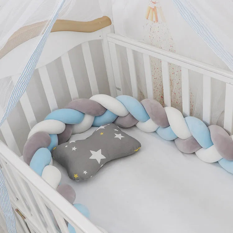 Braided knot baby crib bumper in spandex velvet wrapped around white cot rails.
