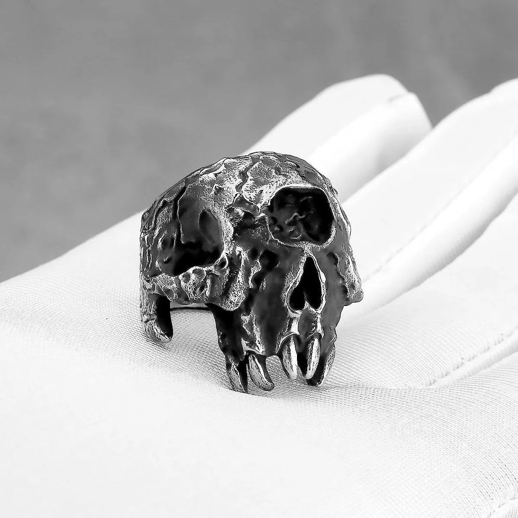A silver-toned alloy ring with a raised one-eyed skull design on a black background.