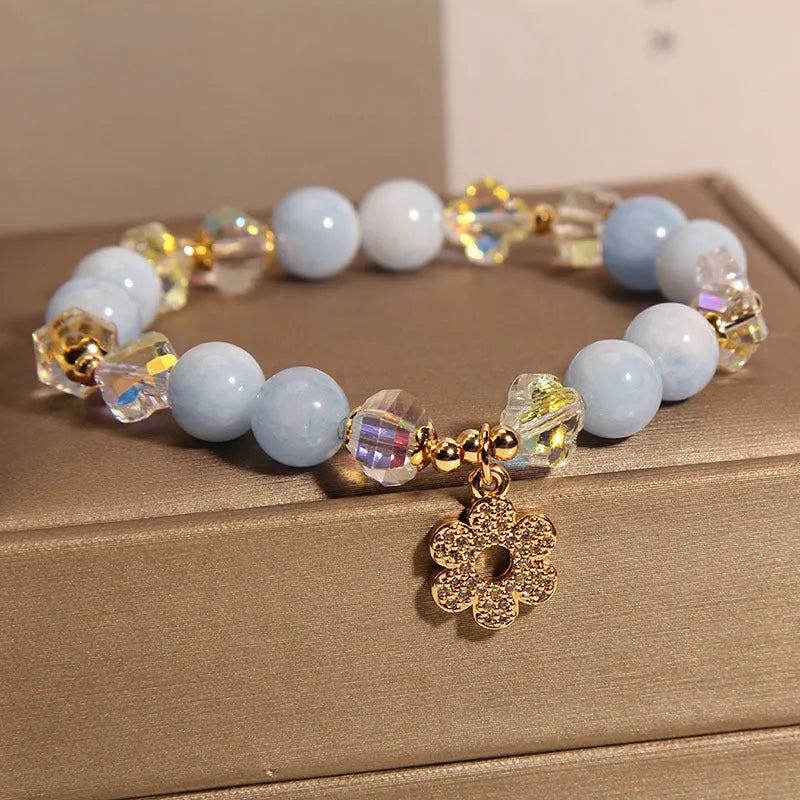 Women's aquamarine crystal bracelet featuring a four-leaf clover charm and pearl decorative elements.