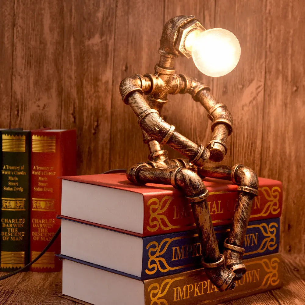 Green bronze vintage industrial iron pipe desk lamp on a wooden table.