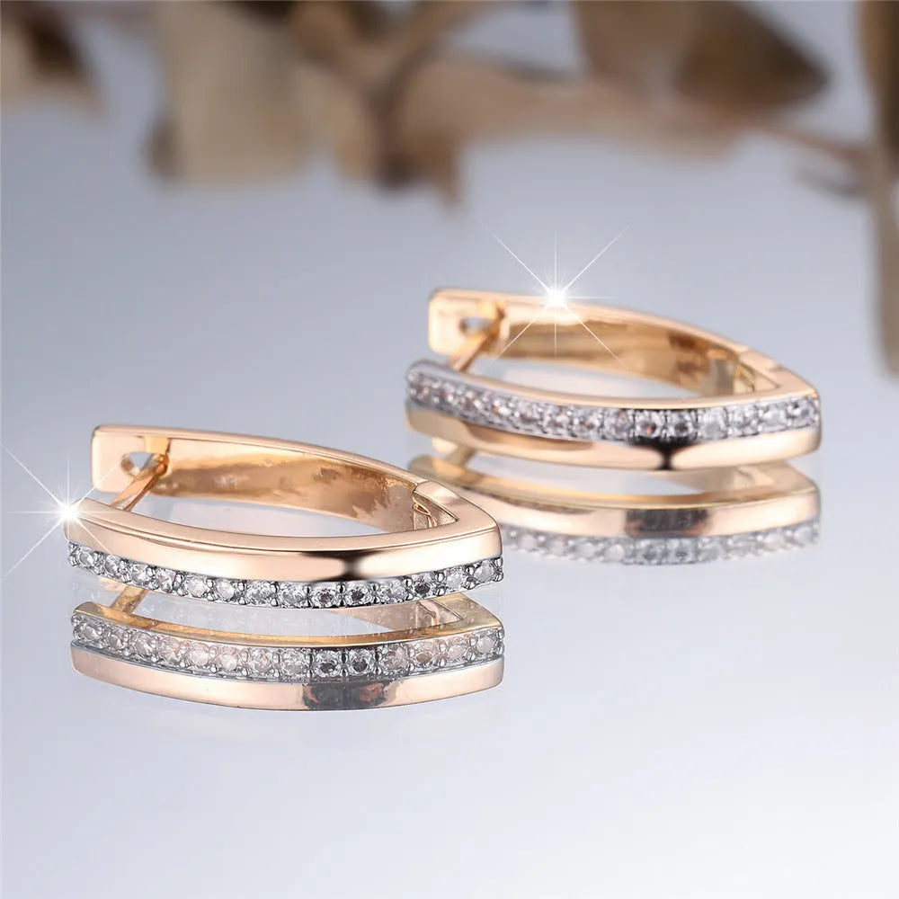 Close-up of women's geometric V-shaped clip-on earrings in champagne gold with white diamond details on a copper base.