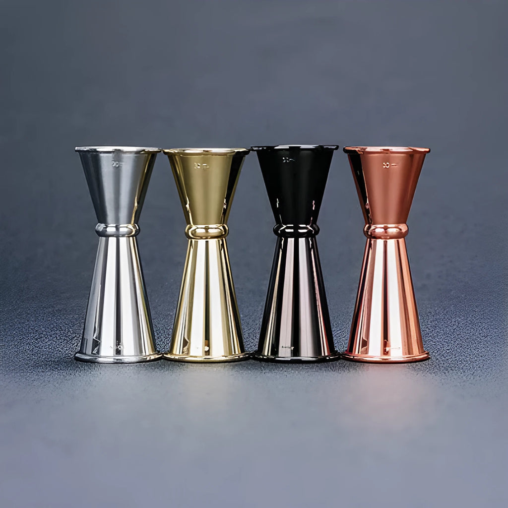 Double-headed stainless steel measuring cup and shaker on a bar counter for cocktail preparation