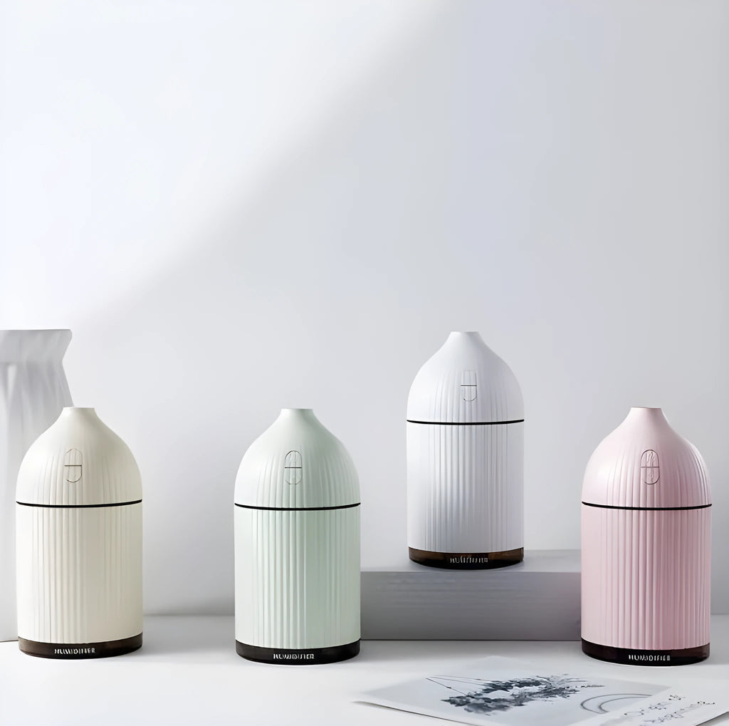 White ultrasonic aromatherapy diffuser with LED light and USB cable on a wooden table