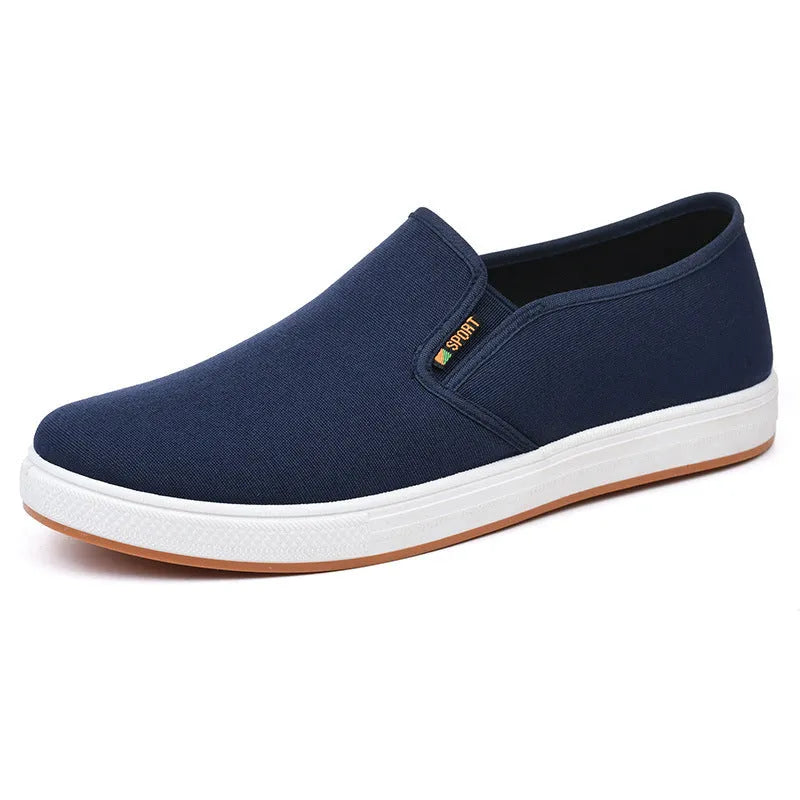 Men's low-top slip-on canvas shoe in blue on a white background, showing round toe and shallow mouth design.