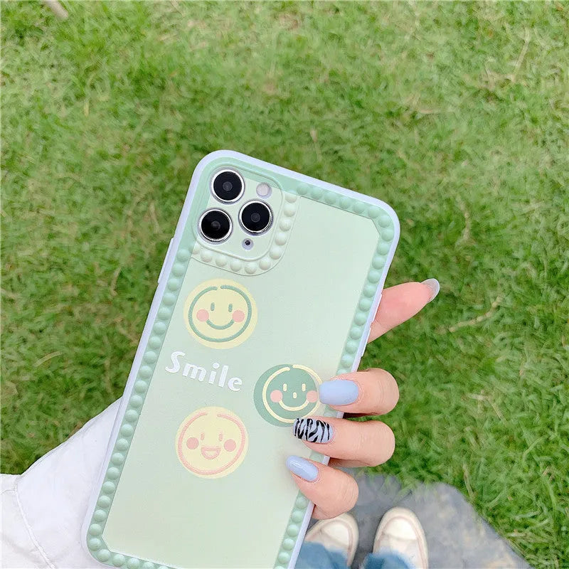 Green TPU phone case with geometric smiley face and polka dot frame design for iPhone.