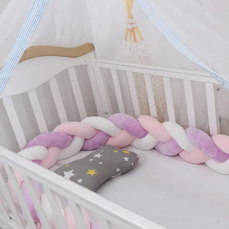 Braided knot baby crib bumper in spandex velvet wrapped around white cot rails.