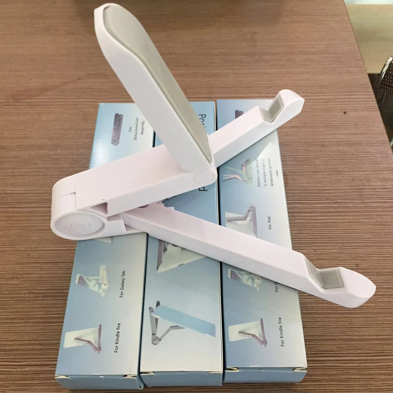 Black foldable aluminium tablet holder open in landscape mode supporting an iPad, showing side adjustment buttons.